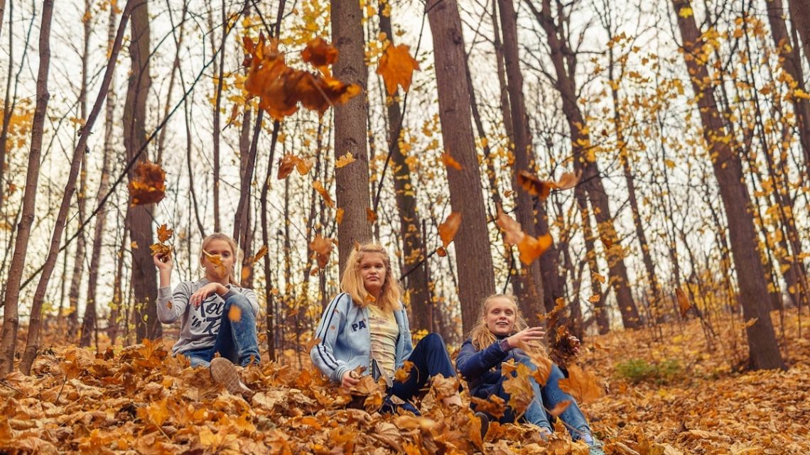 girls throwing autumn leaves in the park and having a good time