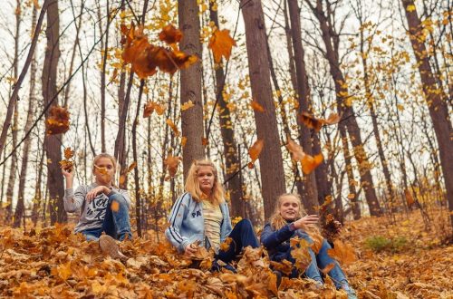 girls throwing autumn leaves in the park and having a good time
