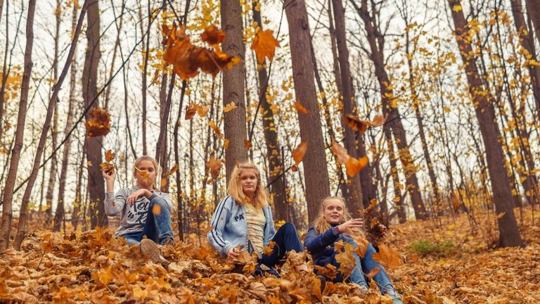 girls throwing autumn leaves in the park and having a good time