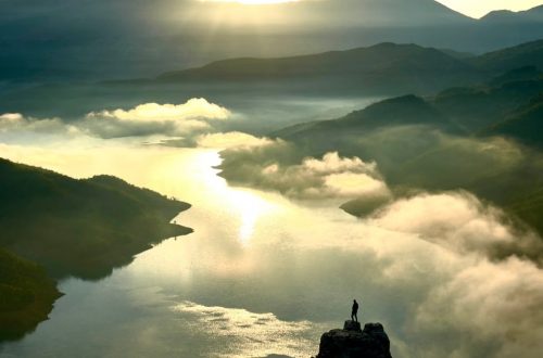 A breathtaking aerial view of the Albanian mountains and river at sunrise, highlighting nature's beauty.