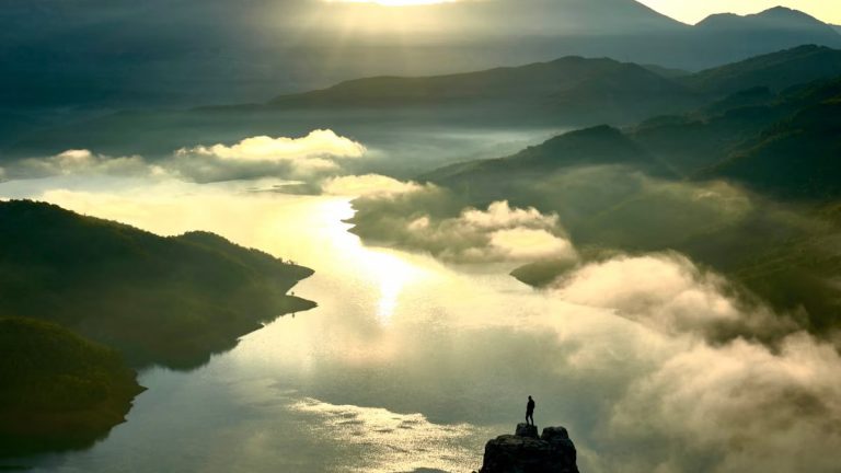 A breathtaking aerial view of the Albanian mountains and river at sunrise, highlighting nature's beauty.
